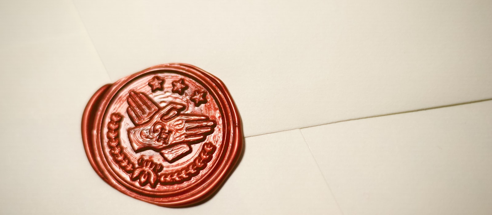 A red wax seal pressed onto a cream envelope