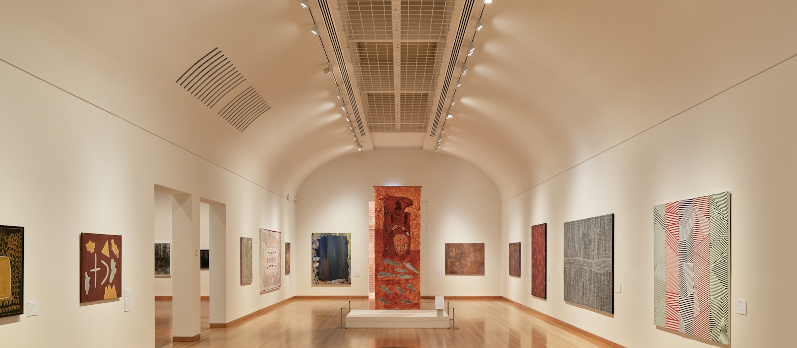 A gallery hall with paintings hung along both walls under track lighting