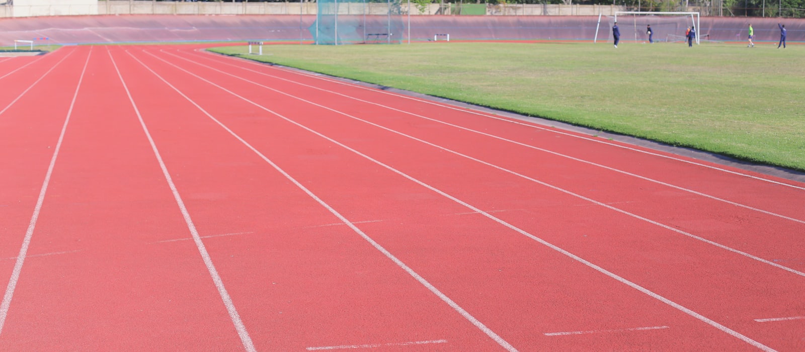 An empty running track with marked lanes beside a grass field