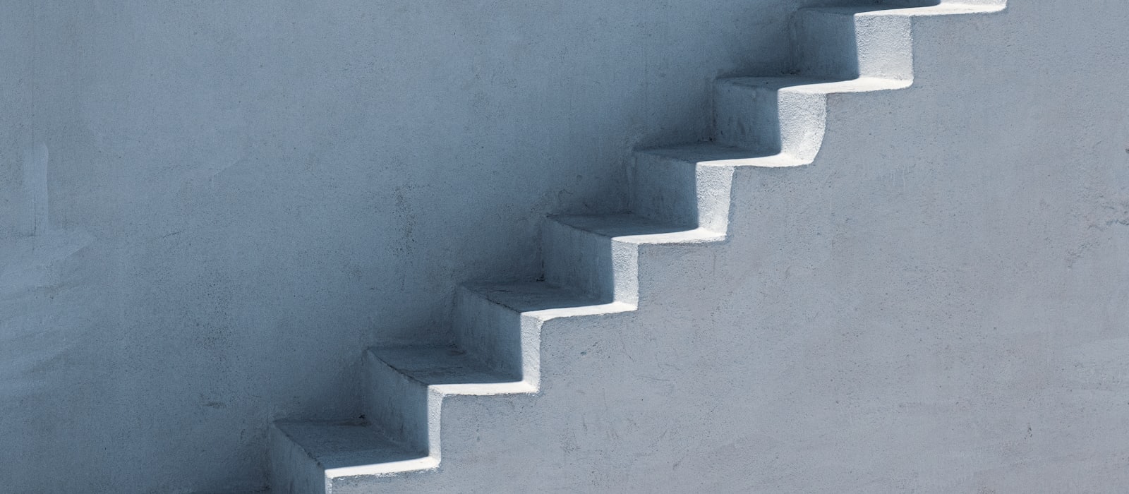 A plain concrete staircase rising against a bare wall