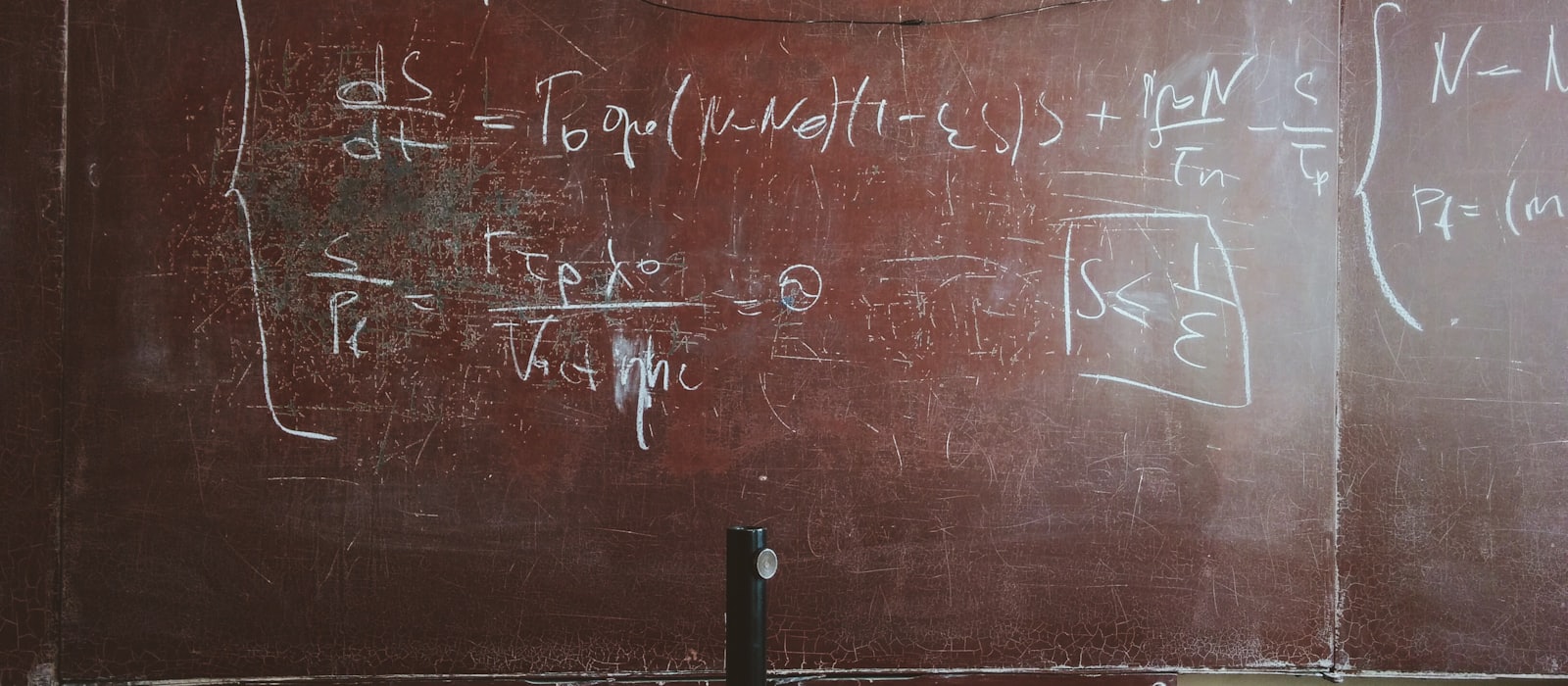 A worn blackboard covered in handwritten equations