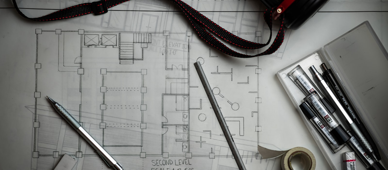 An architectural floor plan on a desk with drafting pencils and a ruler