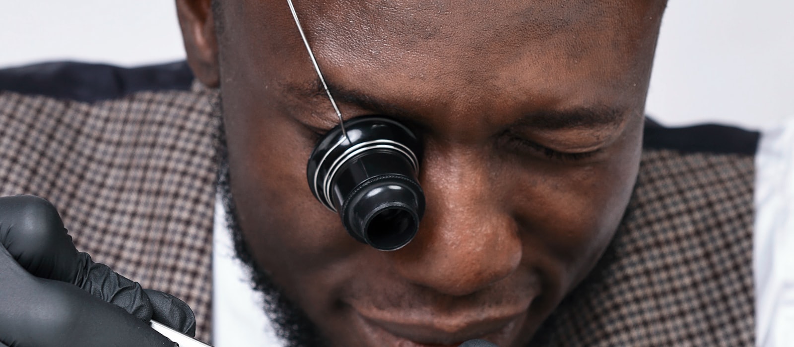 A watchmaker wearing an eye loupe working on a fine mechanism