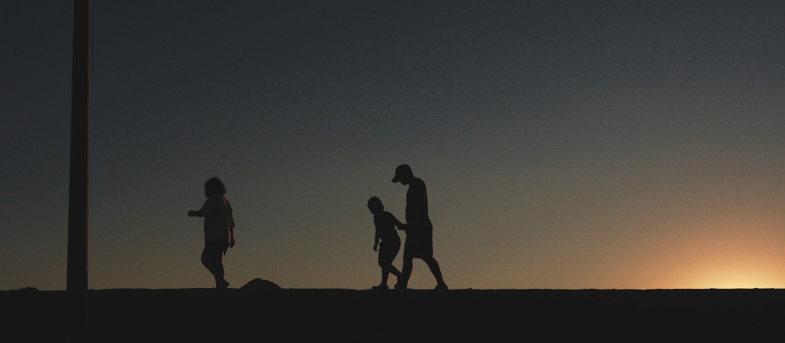 Silhouettes of an adult and children walking together at sunset