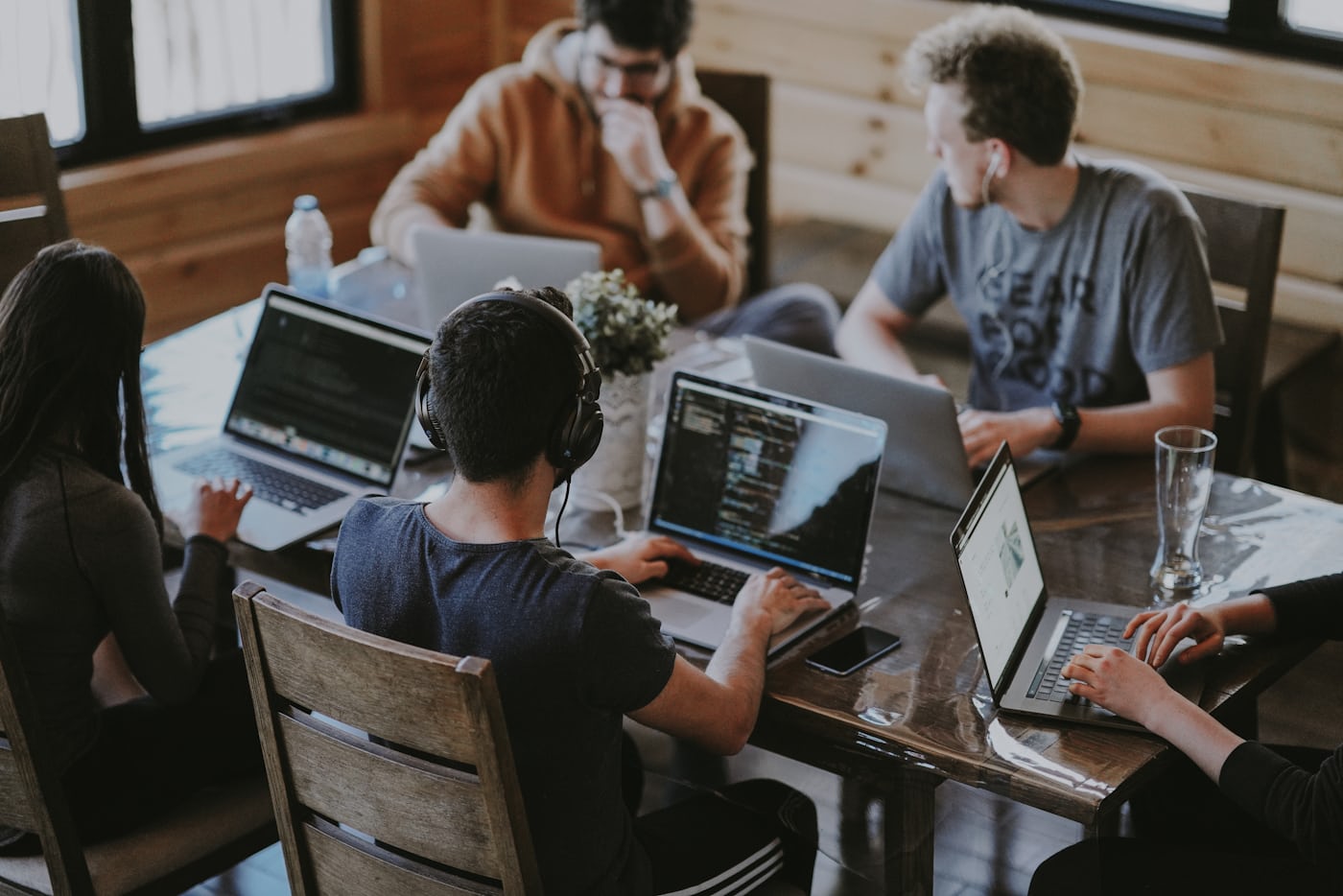 A startup team working together on laptops around a wooden table