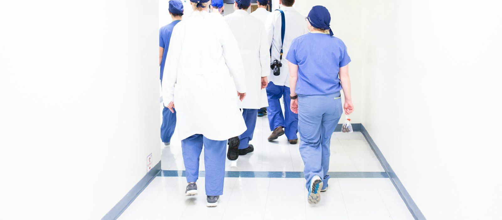 Medical staff in scrubs and white coats walking down a bright hospital corridor