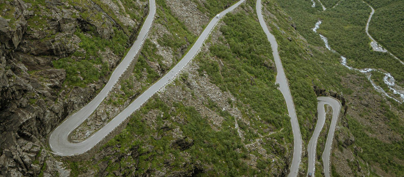 A road winding in hairpin bends up a green mountainside