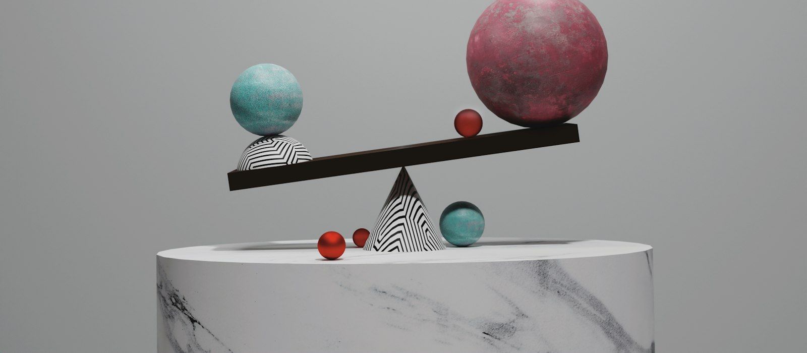 A balance beam on a marble plinth tipped by spheres of different sizes