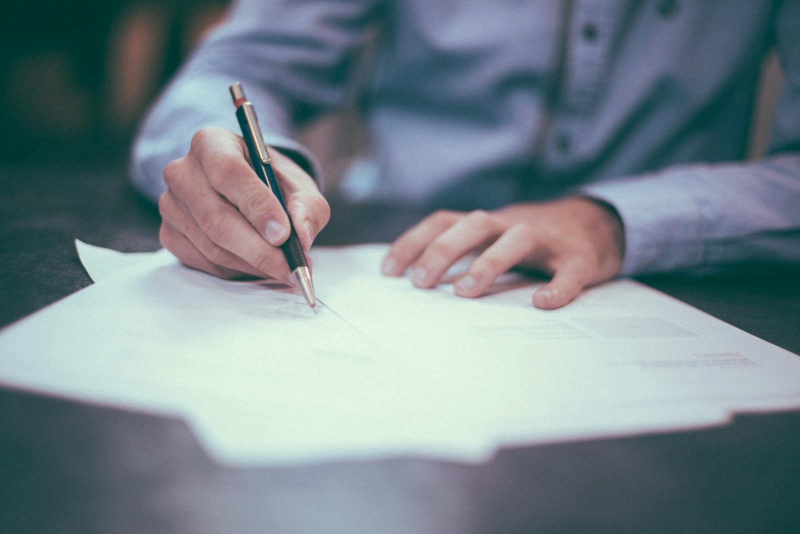 A reviewer working through paperwork with a pen