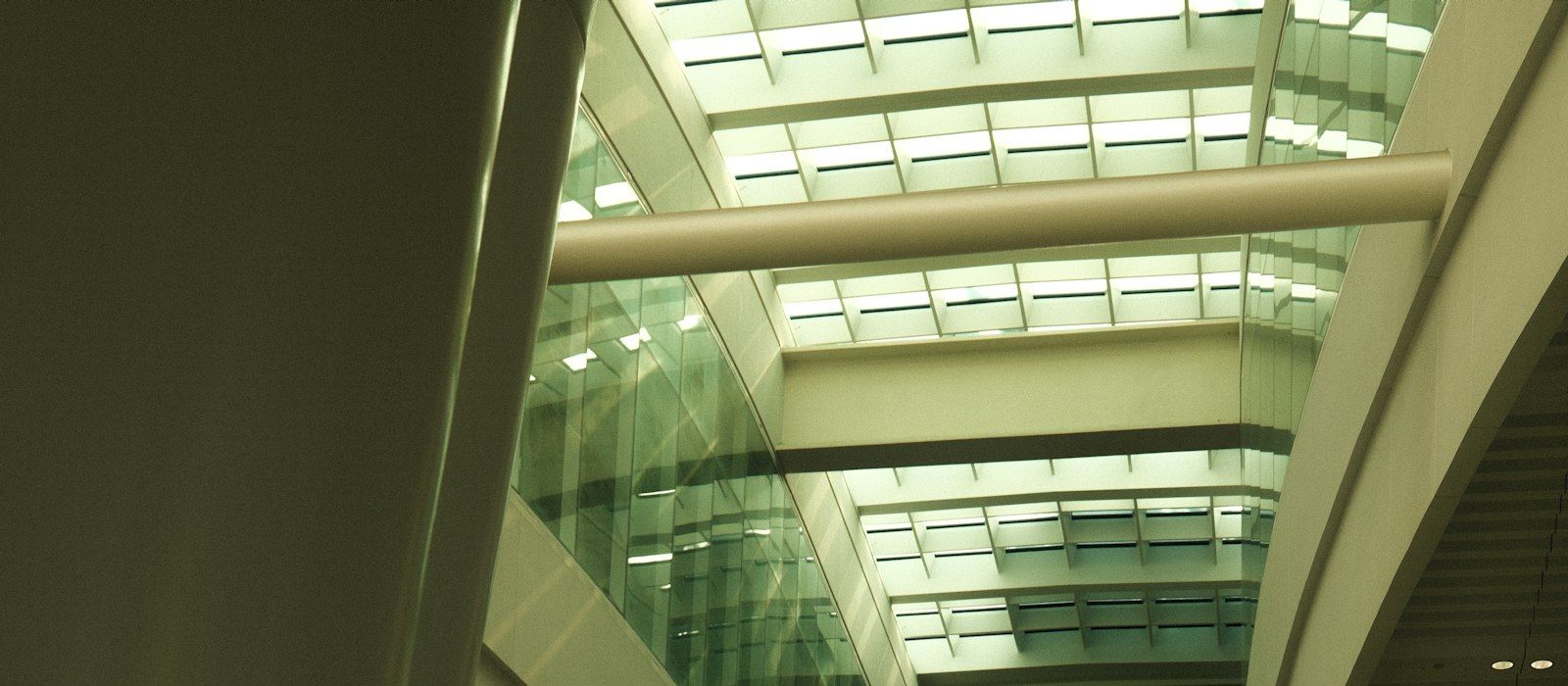 The glass atrium and walkways of a modern office building, seen from below