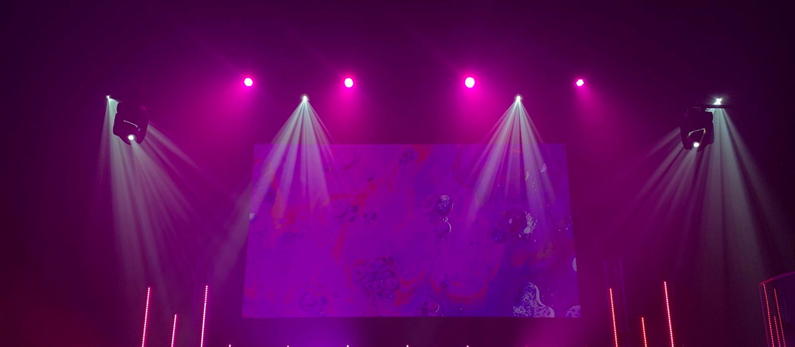Spotlight beams and purple stage lights over an empty concert stage