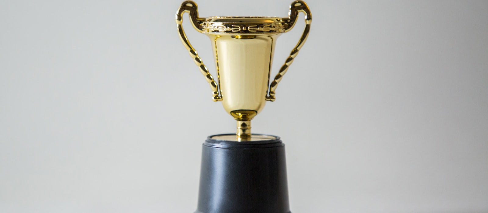 A single gold trophy cup on a plain pale background