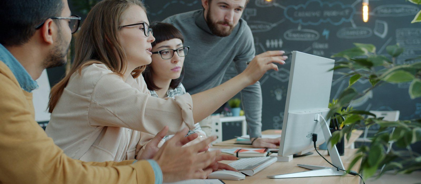 A small team gathered around a desktop computer in a modern office