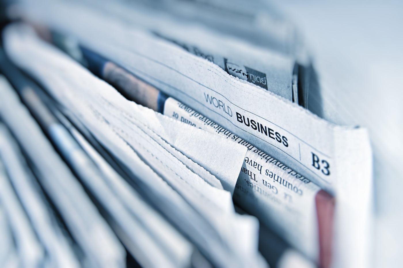 A stack of folded newspapers, the business section visible