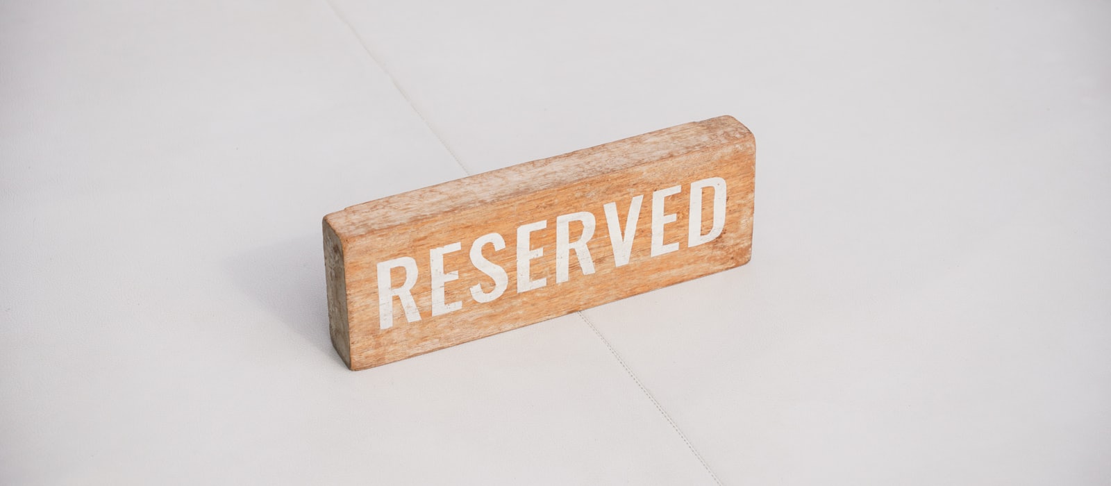 A small wooden sign reading Reserved on a pale surface