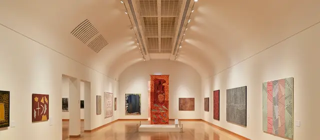 A gallery hall with paintings hung along both walls under track lighting