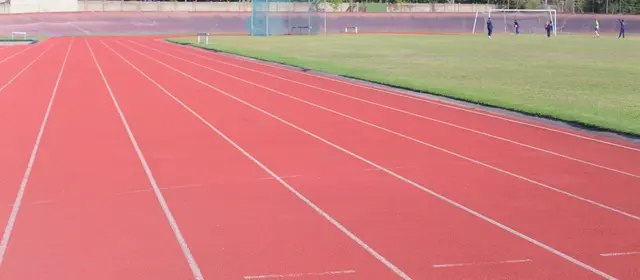An empty running track with marked lanes beside a grass field