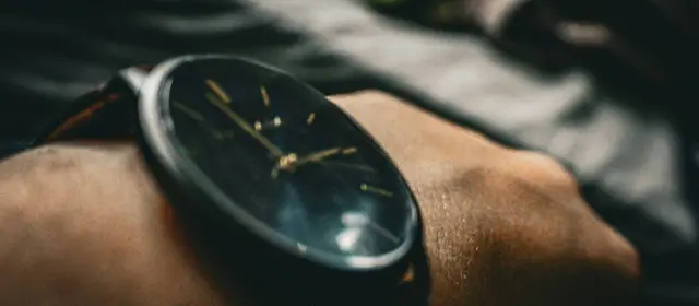 Close-up of a dark analog wristwatch on a person's wrist