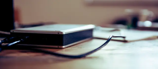 An external hard drive connected on a wooden desk