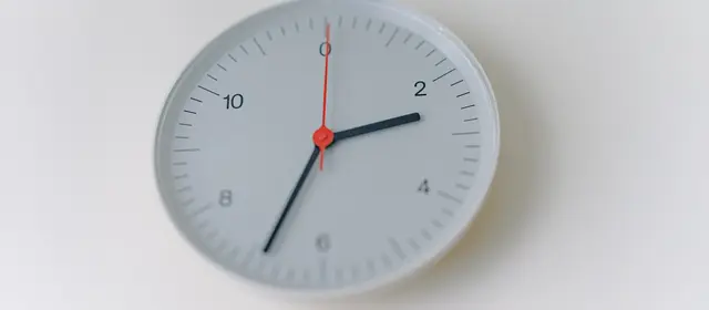 A plain white wall clock with a red second hand