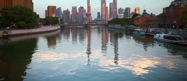 Shanghai skyscrapers reflected in a calm river at dusk