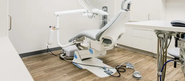 An empty dental treatment chair in a bright, clean clinic room