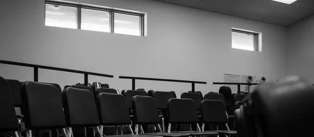 Rows of empty chairs in a quiet room, in black and white
