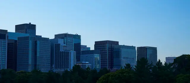 A skyline of corporate office towers rising above trees