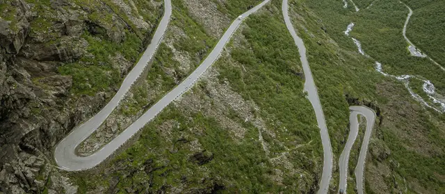 A road winding in hairpin bends up a green mountainside