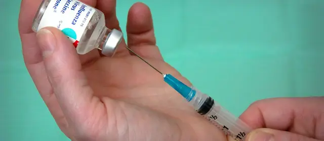 A health worker drawing a vaccine dose from a vial into a syringe