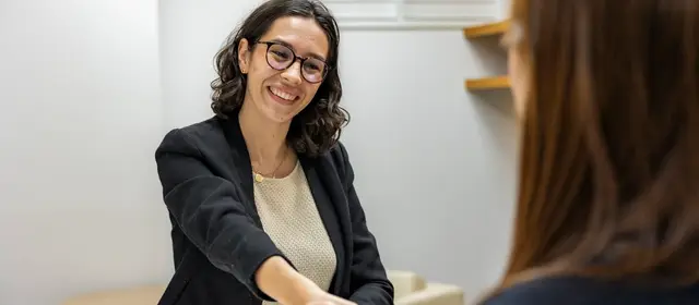 Two people shaking hands across a table in an office