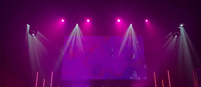 Spotlight beams and purple stage lights over an empty concert stage