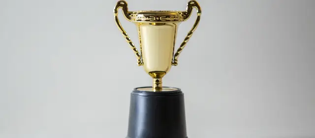 A single gold trophy cup on a plain pale background