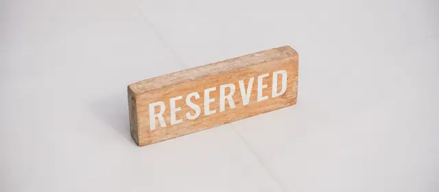 A small wooden sign reading Reserved on a pale surface