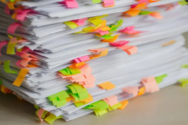 A tall stack of documents indexed with coloured tabs