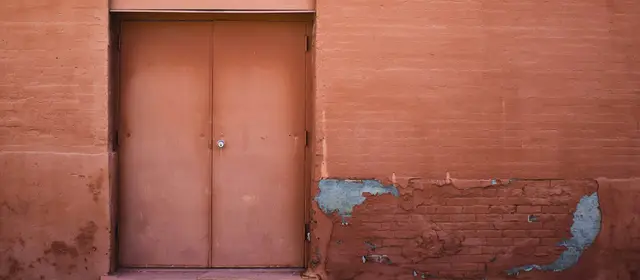 A closed pair of metal doors set in a weathered terracotta wall