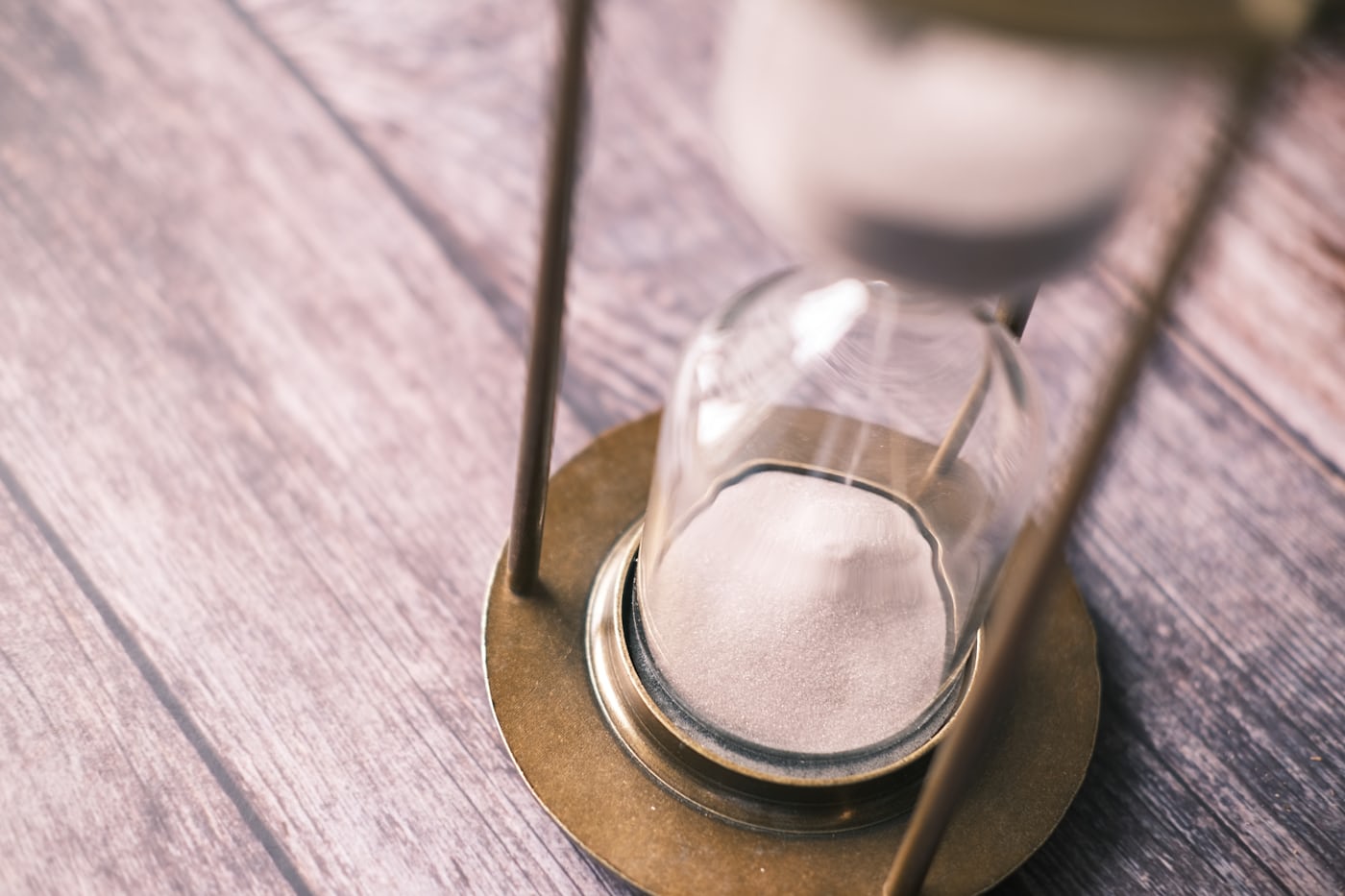 An hourglass on a wooden table with sand running through